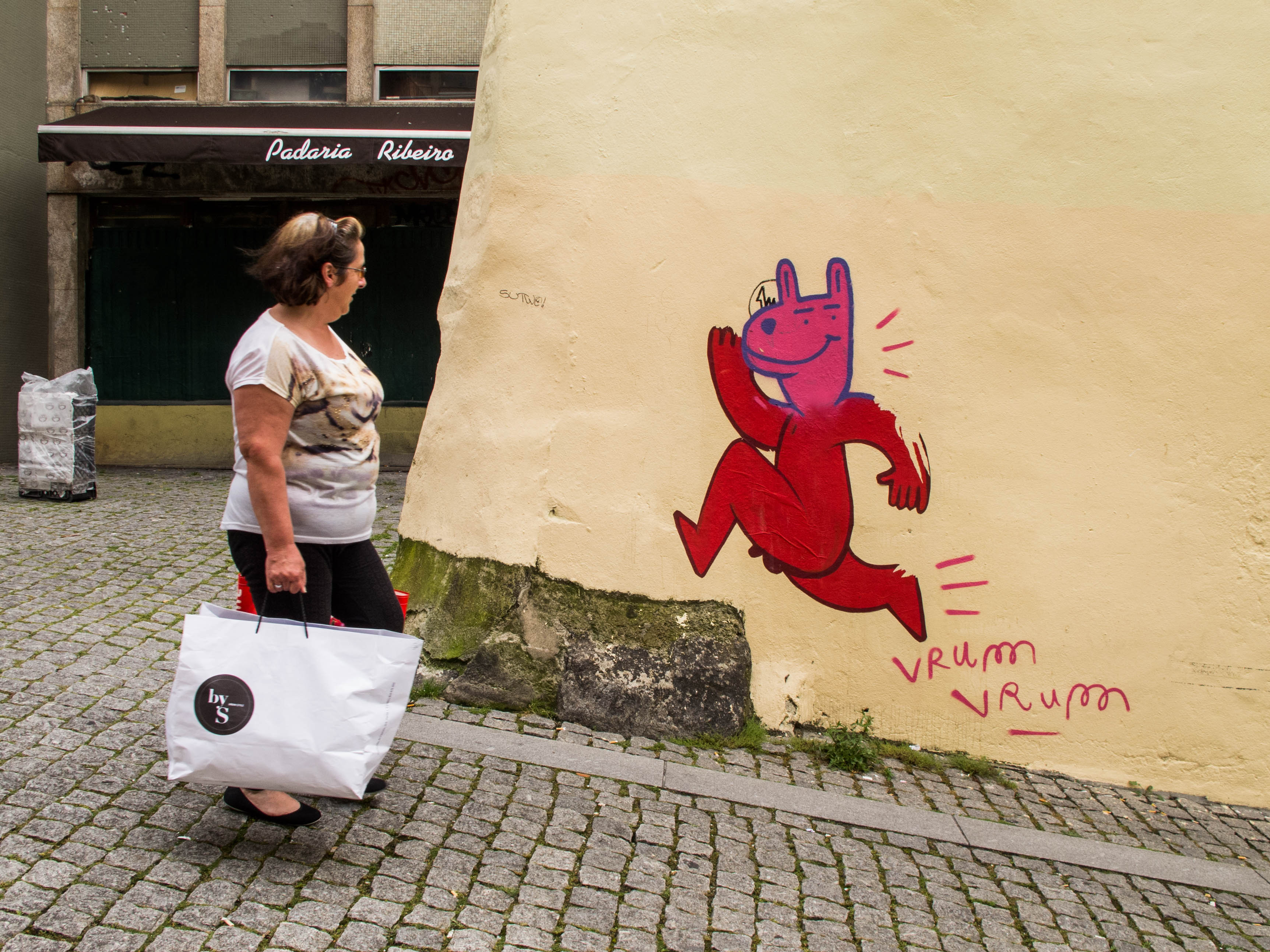 una señora sonrie delante de una jirafa roja en una calle de Oporto