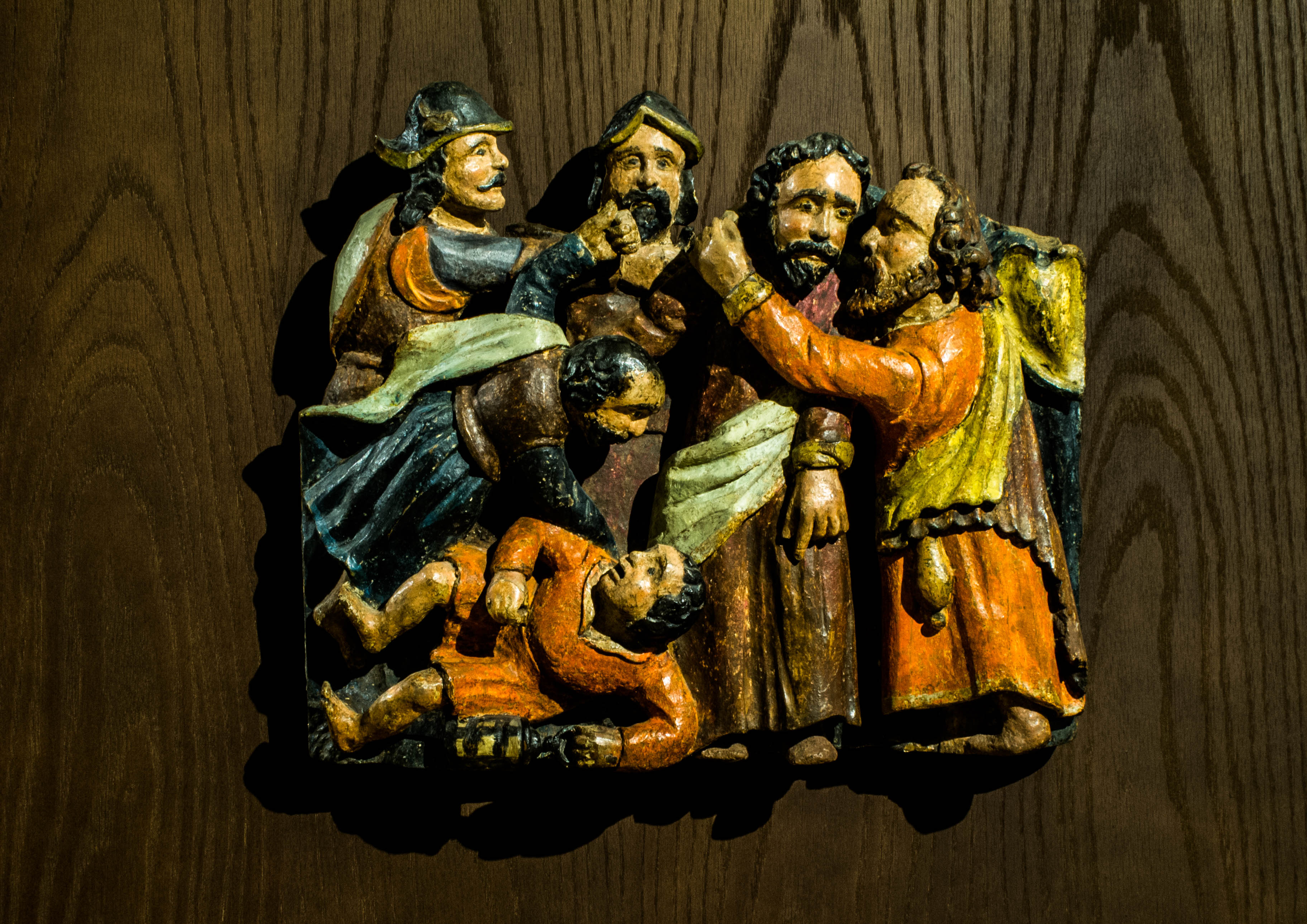 A la derecha, Judas vestido de naranja y con la bolsa con las 30 monedas besa a Jesús. A la izquierda los soldados que detienen a Jesús y abajo uno de los apóstoles corta la oreja a uno de los captores.